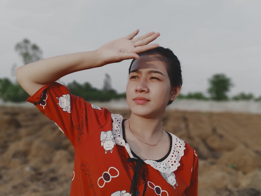 woman in red and white floral shirt raising her hands