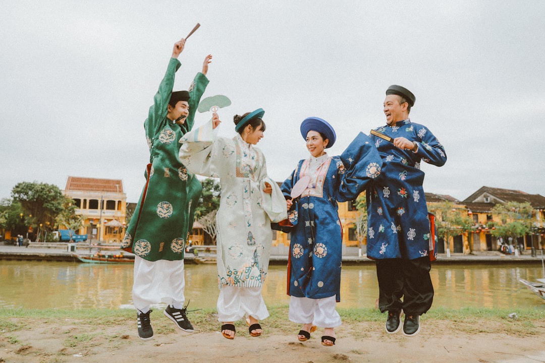 Four people in traditional vietnamese clothing jumping