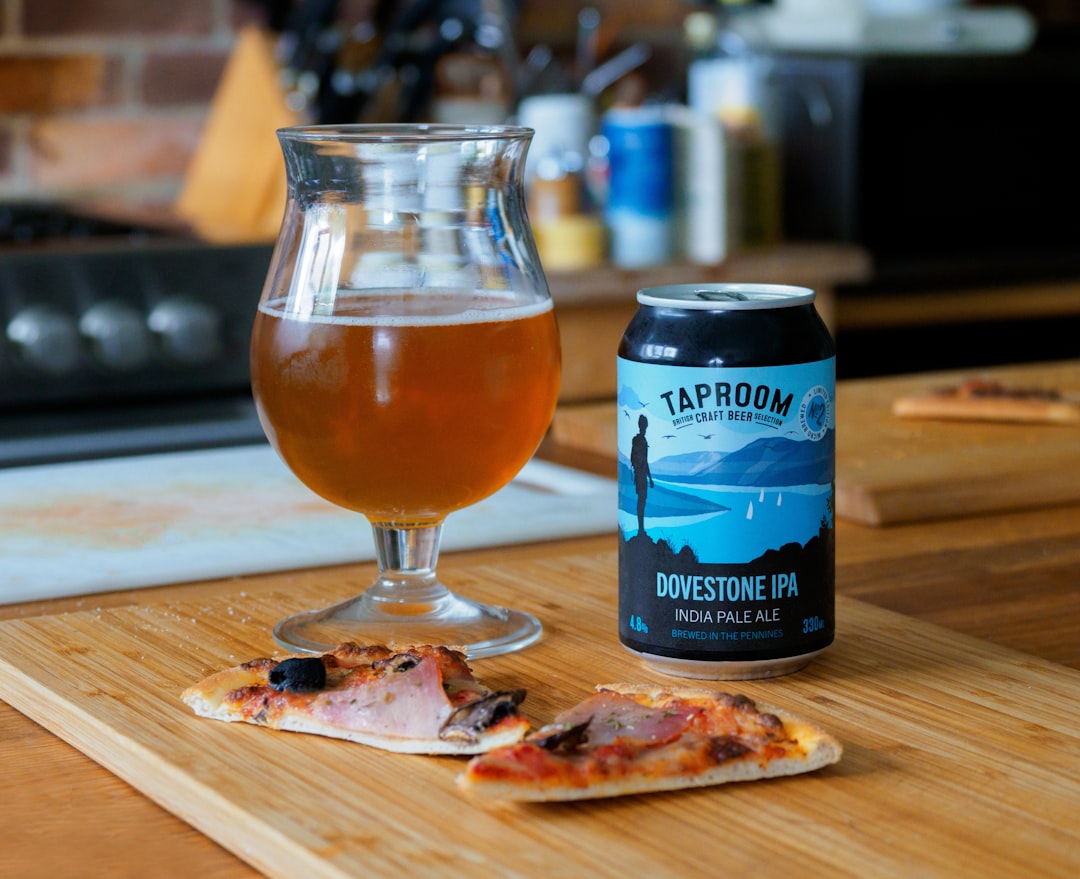 blue and white labeled pack beside clear wine glass on brown wooden table