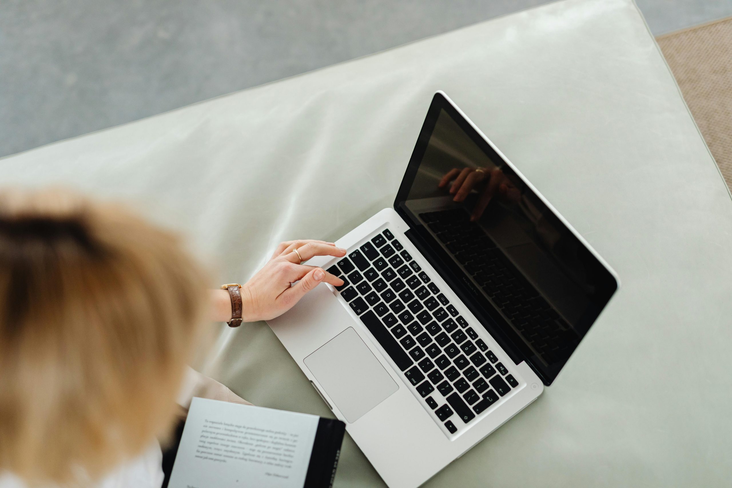 A woman uses a laptop while sitting inside, illustrating remote work lifestyle.